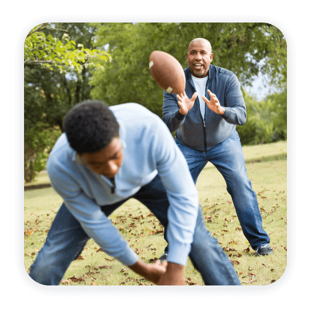 father and son playing football together with hearing aids in